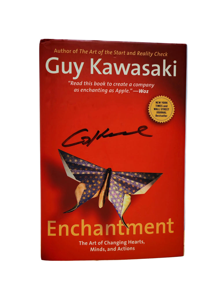 Book titled 'Enchantment' by Guy Kawasaki on a wooden surface with a light blue gradient background